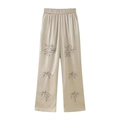 Detail of beaded floral embroidery on apricot satin wide-leg trousers with silk texture - XS / Bottoms / Apricot