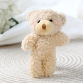 Close-up of a plush teddy bear with pink blush cheeks on a woven mat with floral decor - 11-13cm / Light Brown Blush Bear