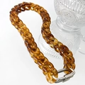 Gros plan d'un collier en chaîne acrylique ambre avec fermoir en métal argenté poli - Collier Ambre Brun Clair