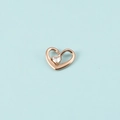 Gros plan du pendentif cœur en or rose avec une pierre étincelante sur fond bleu - Couleur Or Rose Avril
