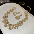 Detailed close-up of floral pearl jewelry set with crystals on a white ceramic tray - Flower Style (HN10918) / Gold