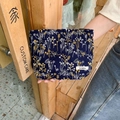 Nahaufnahme der floralen Stickerei auf einer dunkelblauen Stoff-Kosmetiktasche - Marineblau