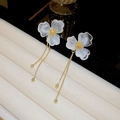 Vista macro de pétalos de mármol blanco y borlas doradas en pendientes de flores - Pasador de Plata - Pendientes de Borla con Flores Blancas