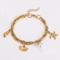 Detalle de los eslabones dorados, el dije de estrella de mar y las conchas de la pulsera - Dorado