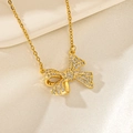 Gros plan du pendentif papillon doré orné de zircons brillants sur fond de tissu élégant - Nœud en Zircon Blanc (F210)