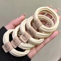 Detail of five beige woven high-elastic hair ties with cute brown bear leather patches - Bear Patch Style / Khaki