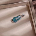 Vue macro d'une broche guitare musicale avec des strass verts incrustés sur métal - Violon / Argent-Vert