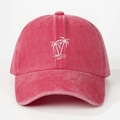 Close-up of white palm tree embroidery on a red washed cotton baseball cap with fabric texture - Watermelon red