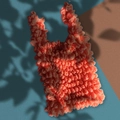 Artistic shot of a coral bubble tote bag with pleat texture on a teal background - Orange Red