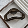 Detail view of a dark translucent jelly-colored hair claw clip in a wooden jewelry box - Fruit Grey