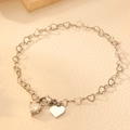 Detalle de la pulsera de cadena con corazones plateados y dije de corazón con pedrería - Color Acero