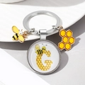 Detailed view of enamel bee keychain with letter G charm and honeycomb pendant - Letter G