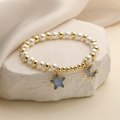 Vue détaillée des pendentifs étoile et lune bleus sur un bracelet de perles et d'or - Violet