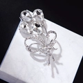 Eleganter silberner Blumenanstecker mit klaren Kristallen auf weißer Marmorfläche - Silber Kristall Blume