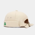 Detailed close-up of a beige cotton miki hat featuring green clover embroidery and metal strap - Adjustable / Off White
