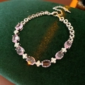 Vista macro dettagliata del bracciale con fiori in zircone rosa su velluto verde scuro - Rosa