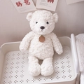 Cute white curly plush teddy bear doll with a brown brand tag in a cozy room decor - White Bear / 35cm