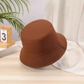 Close-up of a brown cotton bucket hat on a wooden table with soft interior lighting - One Size / Coffee