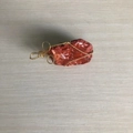 Natural red crystal stone pendant wrapped in golden wire on a light wood background - Gold Wire Red Jasper