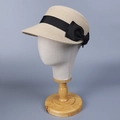 Detail eines eleganten beigen Stroh-Reiterhuts mit schwarzer Schleife auf Modell - Beige