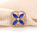 Macro detail of golden clover brooch featuring blue marquise gems and clear crystals - Royal Blue