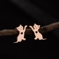 Detail of rose gold cat stud earrings with hollow heart design on a natural branch - Rose Gold