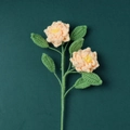 Handgestrickter Garn-Blumenstrauß mit rosa Rosen und grünen Blättern auf dunklem Grund - Hellrosa Gardenienzweig