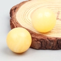 Spherical yellow amber crystal stones shown on a natural wood base decoration - Yellow Topaz/Honey Jade