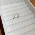 Elegant white pearl stud earrings with golden pins on a beige linen jewelry display box - 10mm/Gold Plated / White (10mm)