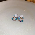 Dettaglio di orecchini a fiore in oro rosa con strass blu e perle bianche su ceramica - Fiore di Strass Blu (Ago d'Argento) / Blu