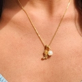 Collar dorado con colgante de bota y perla, vista detallada sobre el cuello - Bota de Vaquero