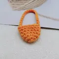 Detailed view of handmade orange crochet mini crossbody bag with knitted handle and hollow texture - Orange