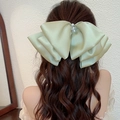 Large light green satin bow hair clip with pearl detail shown on brown wavy hair - Matcha Green Artificial Pearl Bow Spring Clip