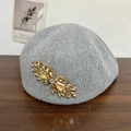 Sparkly grey knitted beret for women featuring crystal wing ornament on wooden surface - Gray