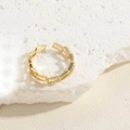 Dettaglio macro di un anello a catena dorato con zirconi su una superficie in pietra - Placcato Oro Quadrato Geometrico