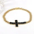 Detailed close-up of a golden chain bracelet featuring a black gemstone cross pendant - Black