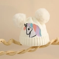 Nahaufnahme der weißen Strickmütze mit Einhorn-Stickerei und flauschigen Doppel-Pompons - Einheitsgröße (2-6 Jahre) / Weiß