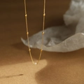 Minimalist freshwater pearl necklace in 18K gold plated stainless steel on a brown backdrop - Gold