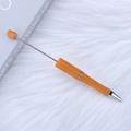 Creative DIY orange beaded ballpoint pen with silver metal rod on white faux fur background - Willow Orange