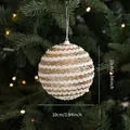 Sparkly white and gold striped Christmas ball ornament hanging on a festive tree branch - Champagne Foam Ball