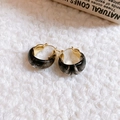 Détail de boucles d'oreilles vintage en résine en U avec texture marbre sur fond peluche - Noir Doré