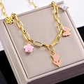 Detailed shot of golden link bracelet with pink enamel tulip and bee charms on box - Necklace