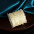 Cream yellow 0.8mm polyester cord spool on dark wood tray with teal satin background - Beige
