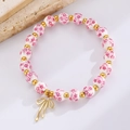 Dettaglio di perline in ceramica floreale e ciondolo a fiocco dorato su bracciale - Stile Fiocco Perline di Ceramica Rosa Floreale (1880)