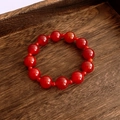 Macro shot of red agate beaded bracelet with polished translucent finish on wood tray - Single Strand Large Round Bead Style