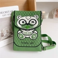 Detail of green knitted phone bag featuring a panda pattern and adjustable strap - Glasses Bear Green