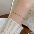 Bracciale minimalista con perline d'oro da donna mostrato al polso in stile elegante - Bracciale / Oro