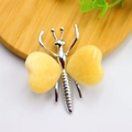 Silver butterfly ornament with yellow heart-shaped gemstone wings on wood surface - White K Plated Topaz Stone