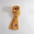 Cozy yellow knitted kids scarf in soft wool with a small purple tag on white background - Purple Leather Label / Yellow