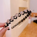 Cerchietto nero ondulato con fiori di strass champagne tenuto in mano da donna - Cerchietto con fiori di prugno in strass champagne